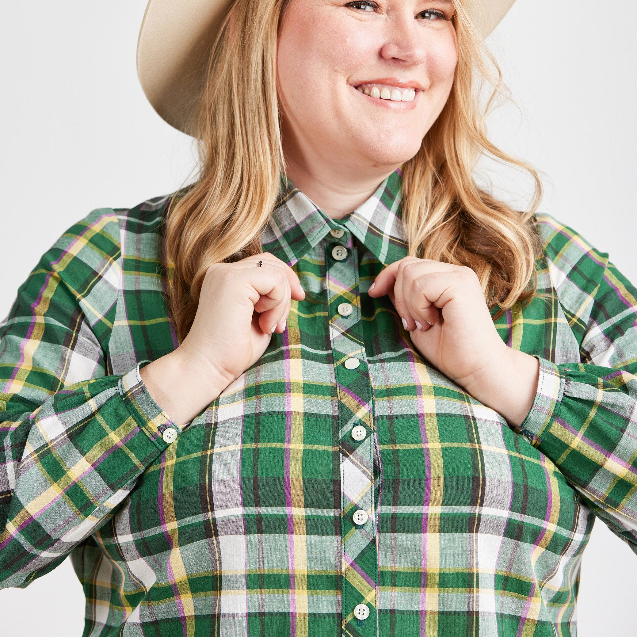 Person wearing a green plaid shirt with a beige hat on a white background. This top is the Vernon Shirt sewing pattern from Cashmerette.