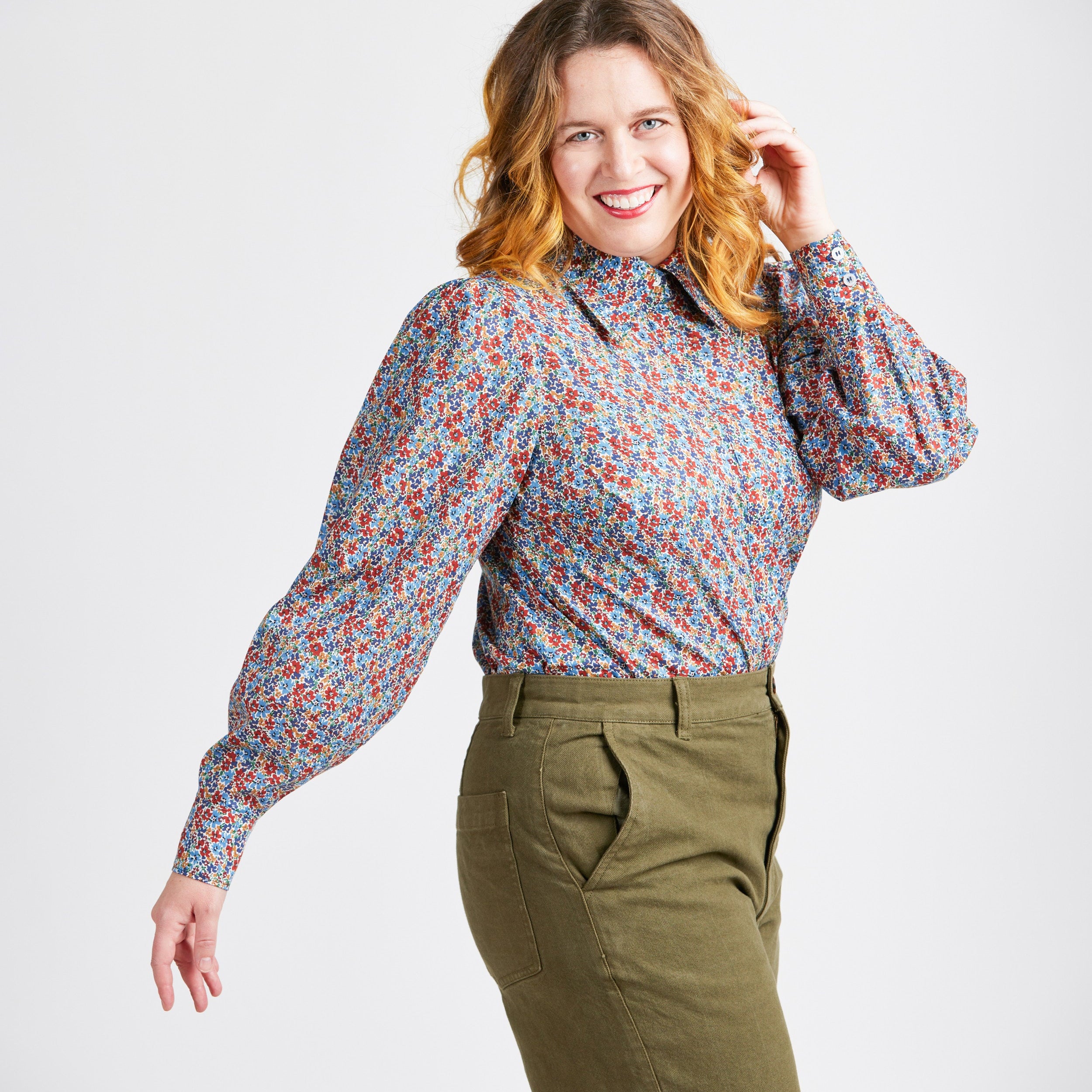 Woman wearing a patterned blouse and green pants on a white background. This top is the Vernon Shirt sewing pattern from Cashmerette.