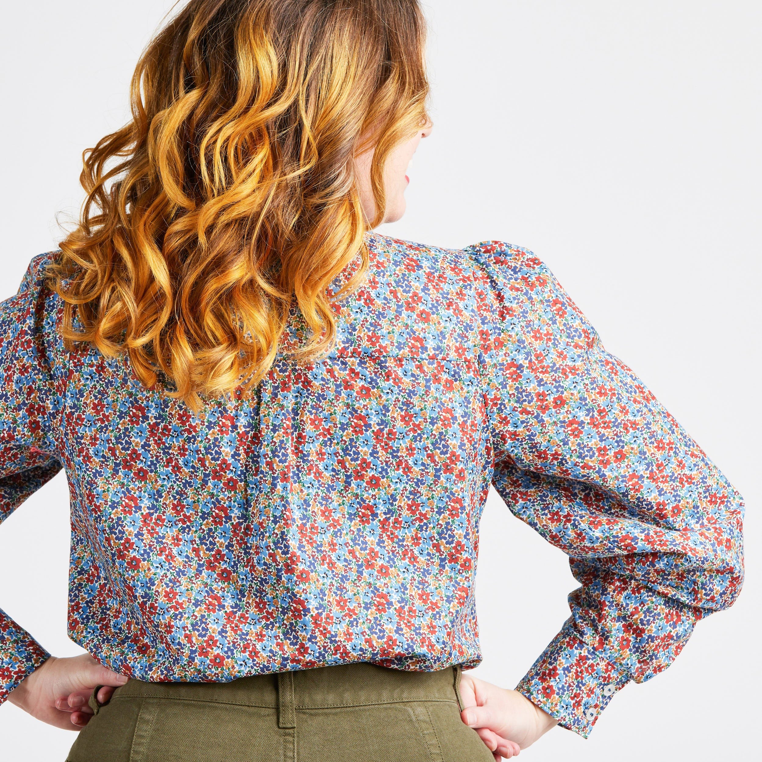 Woman wearing a floral blouse with long sleeves on a plain background. This top is the Vernon Shirt sewing pattern from Cashmerette.