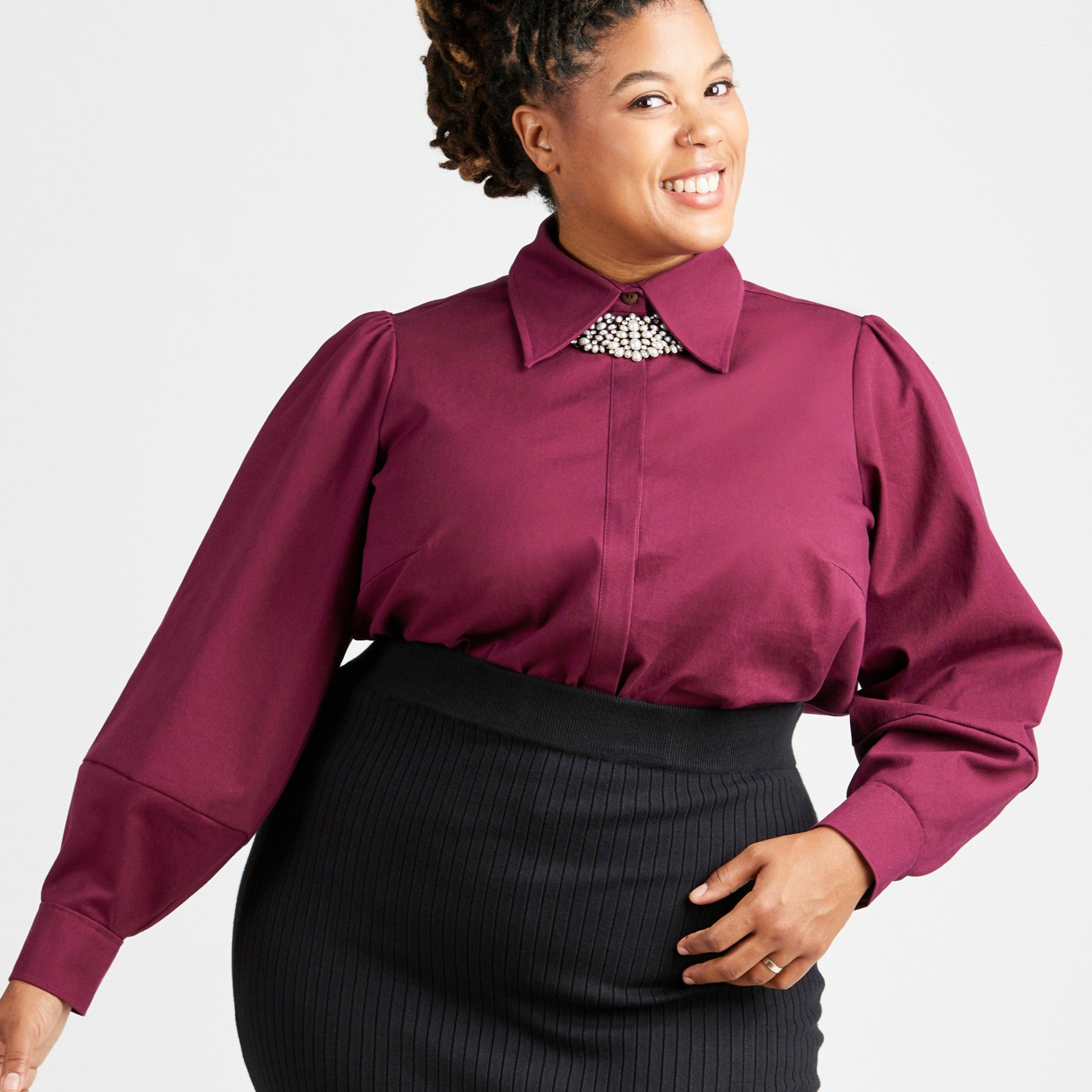 Woman wearing a burgundy blouse with a decorative collar against a white background. This top is the Vernon Shirt sewing pattern from Cashmerette.