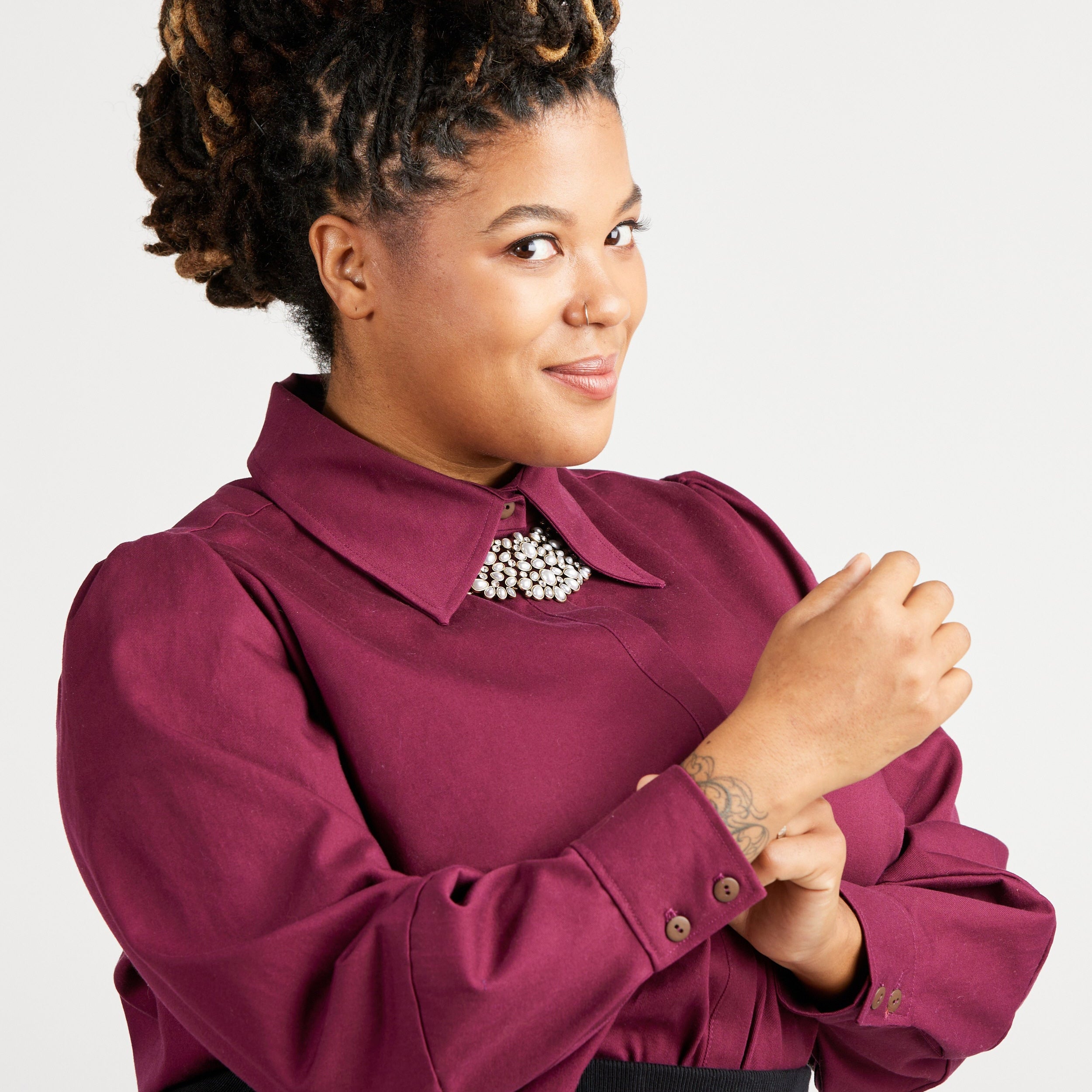 Woman wearing a burgundy shirt with a white background. This top is the Vernon Shirt sewing pattern from Cashmerette.