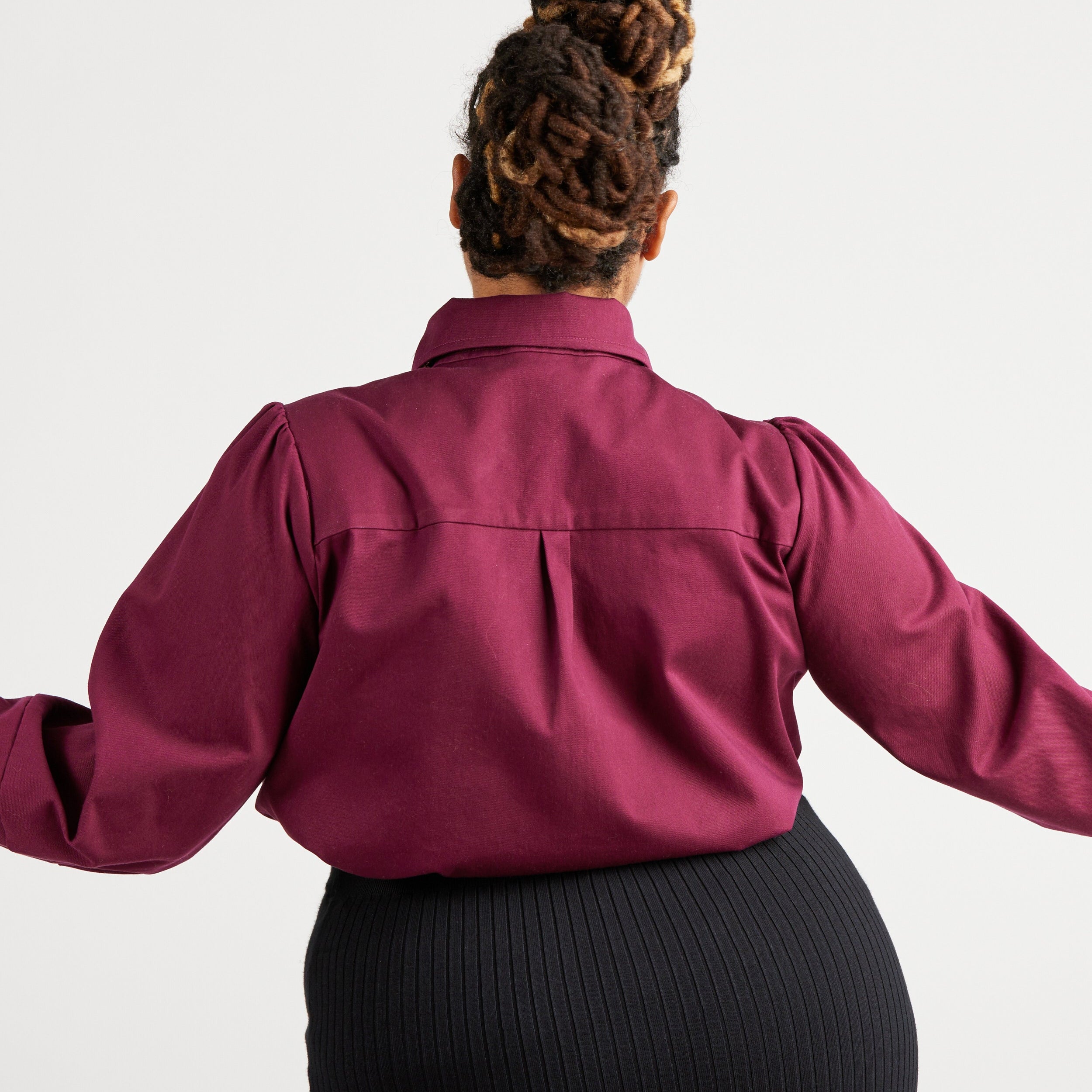 Person wearing a burgundy shirt with long sleeves on a white background. This top is the Vernon Shirt sewing pattern from Cashmerette.