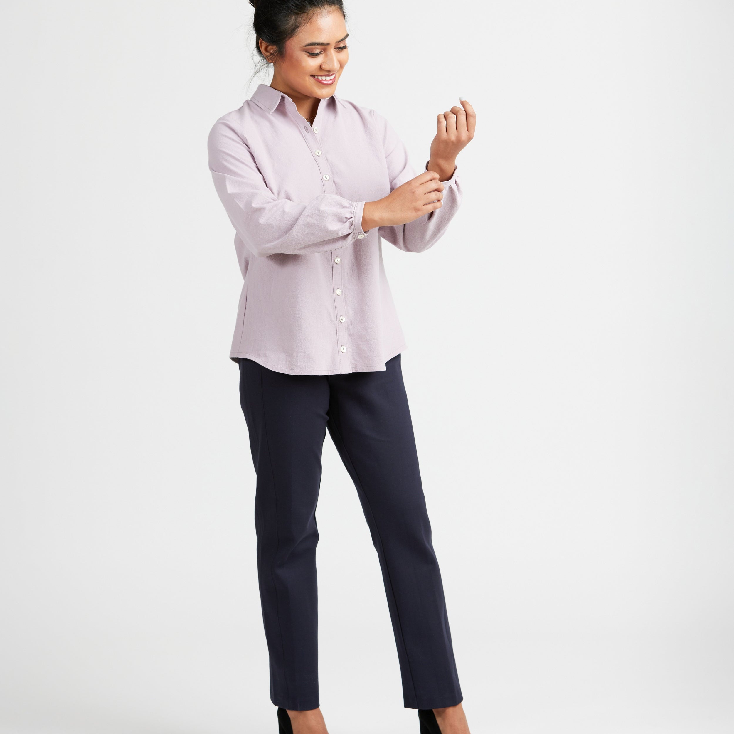 Woman wearing a light pink blouse and dark pants on a white background. This top is the Vernon Shirt sewing pattern from Cashmerette.
