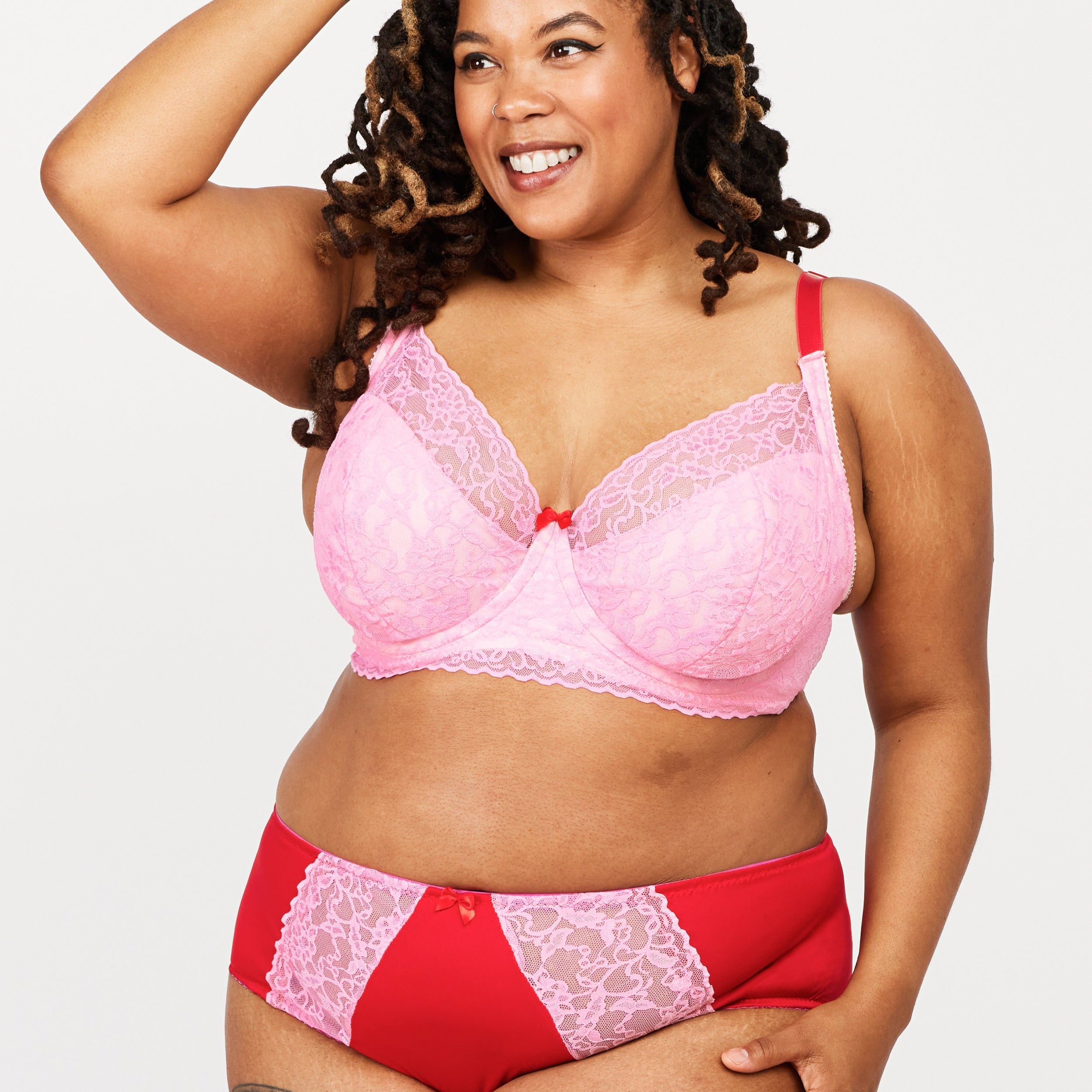 Woman wearing a pink and red lingerie set on a white background. This bra is the Willowdale Bra sewing pattern from Cashmerette.