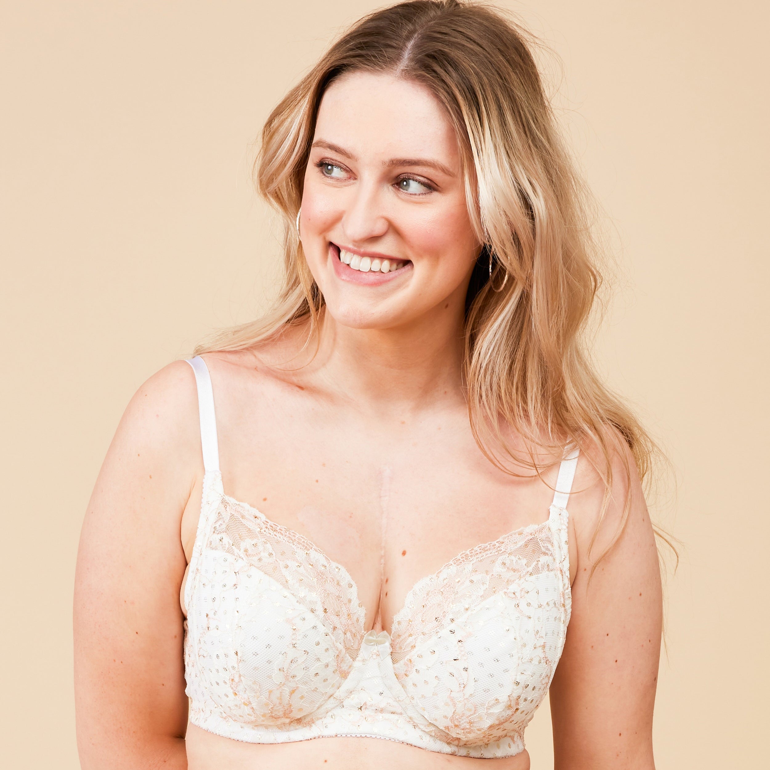 Woman wearing a white lace bra against a beige background. This bra is the Willowdale Bra sewing pattern from Cashmerette.