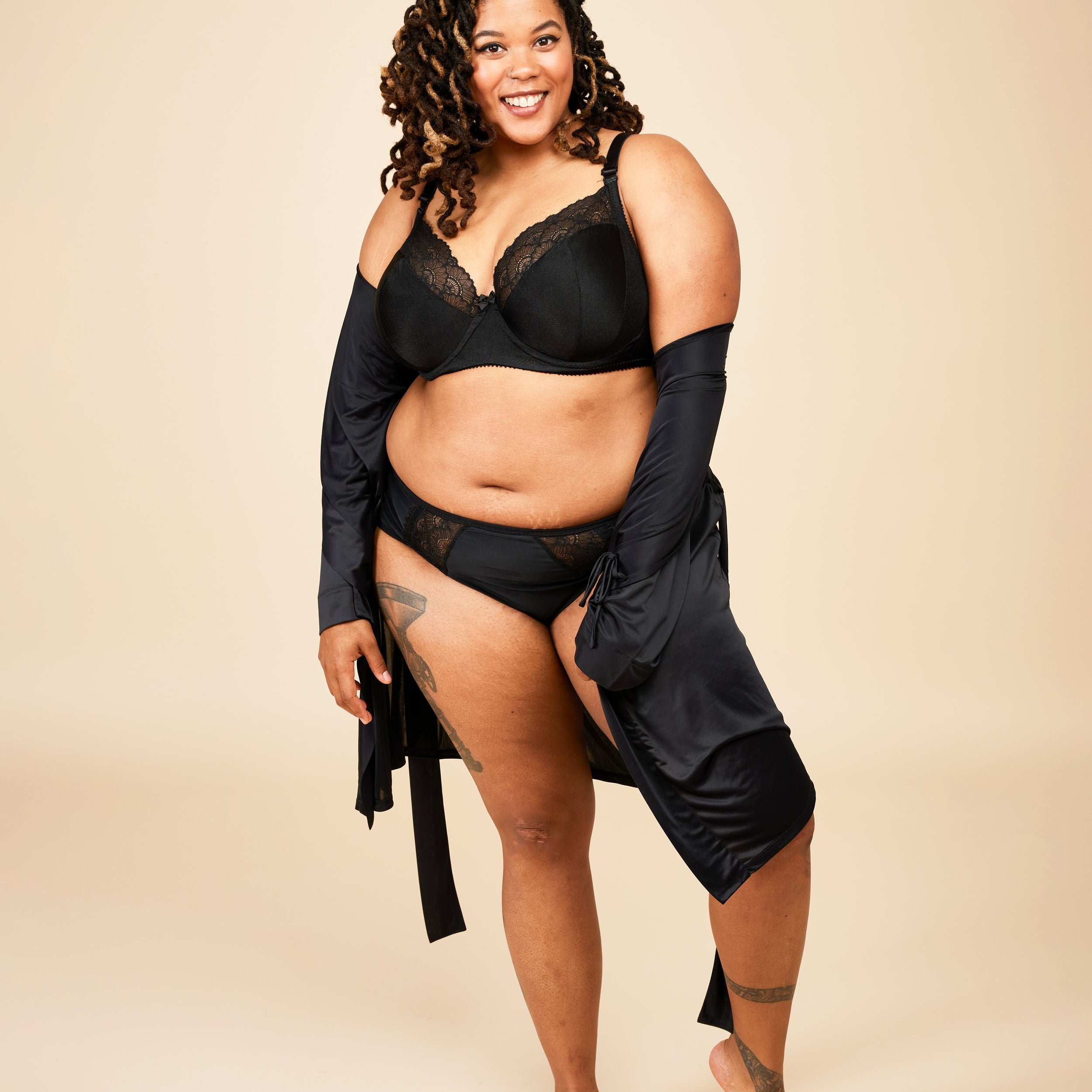 Woman wearing a black lingerie set with a beige background. This bra is the Willowdale Bra sewing pattern from Cashmerette.