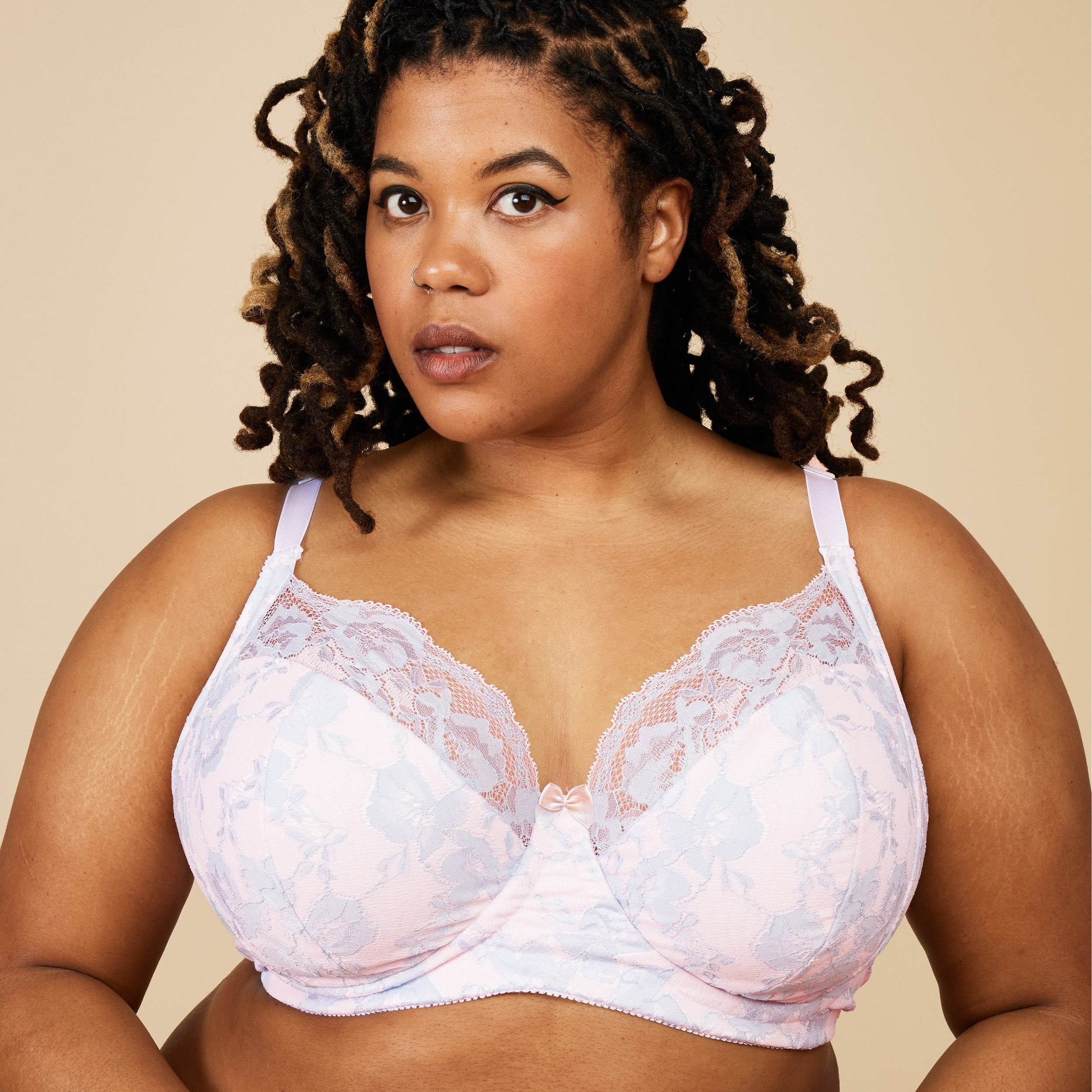Woman wearing a white lace bra against a beige background. This bra is the Willowdale Bra sewing pattern from Cashmerette.