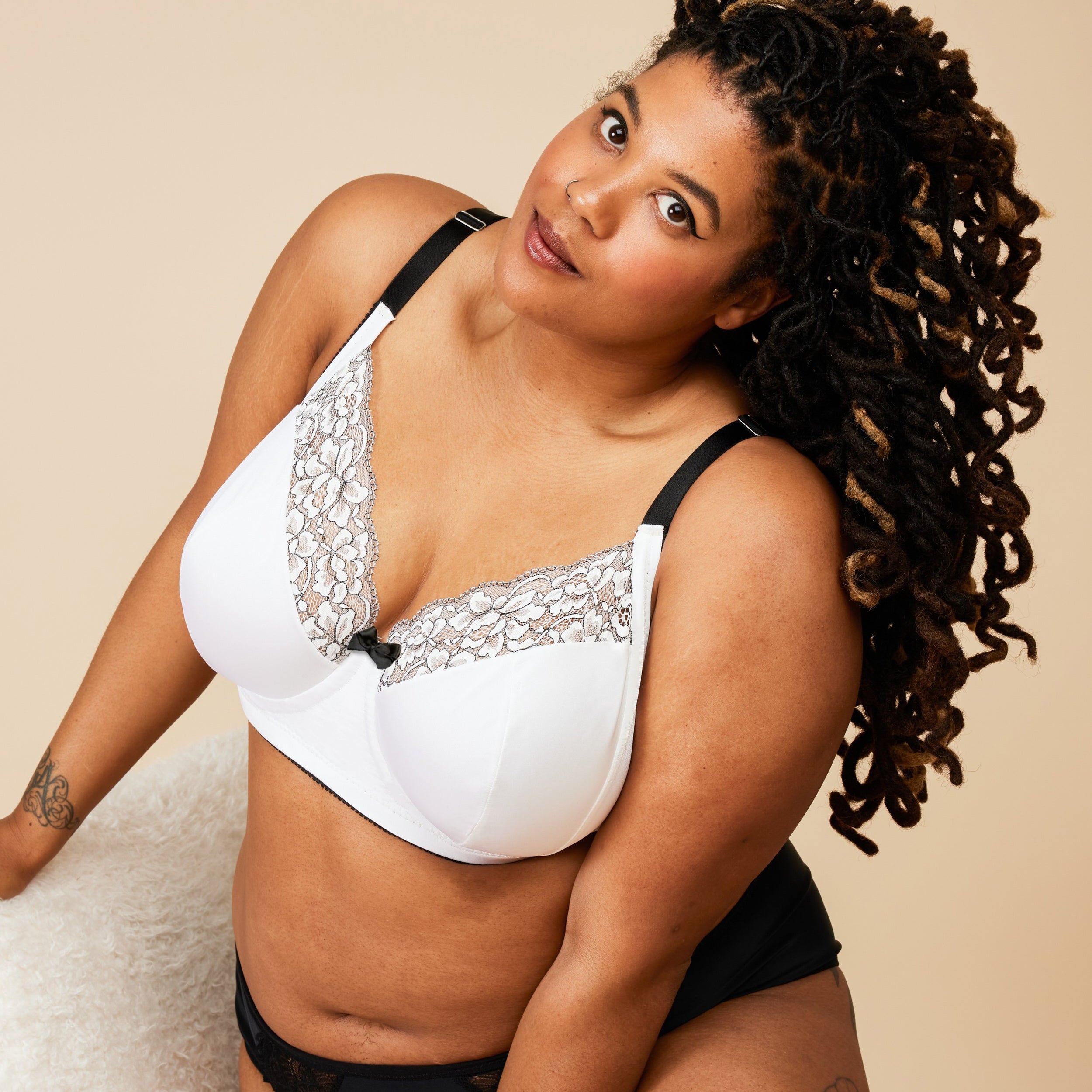 Woman wearing a white bra with lace details and black underwear on a beige background. This bra is the Willowdale Bra sewing pattern from Cashmerette.