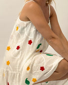 White dress with colorful floral patterns worn by a person on a plain background