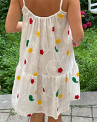 White dress with colorful floral patterns worn by a person outdoors.