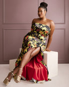 Woman in a floral strapless dress sitting on a white cube against a purple wall. This dress is the Ellington Strapless Dress sewing pattern from Cashmerette.