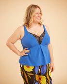 Woman wearing a blue top with floral pants on a beige background. This is the Fiske Sleepwear Set sewing pattern from Cashmerette.