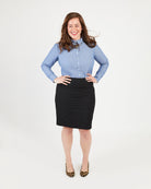 Woman wearing a light blue shirt and black skirt on a white background. This button-up shirt is the Harrison Shirt sewing pattern from Cashmerette.