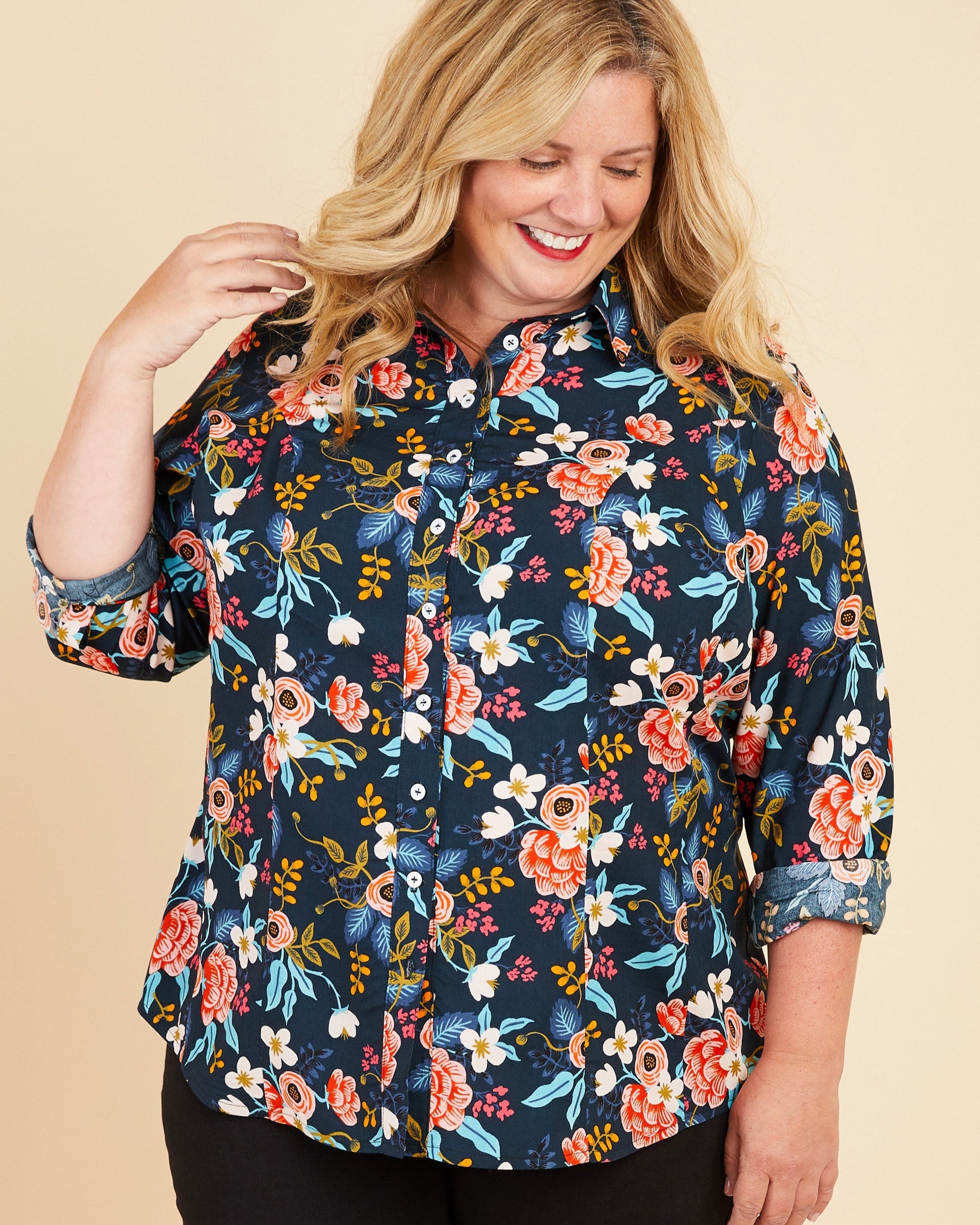 Woman wearing a floral blouse on a beige background. This button-up shirt is the Harrison Shirt sewing pattern from Cashmerette.