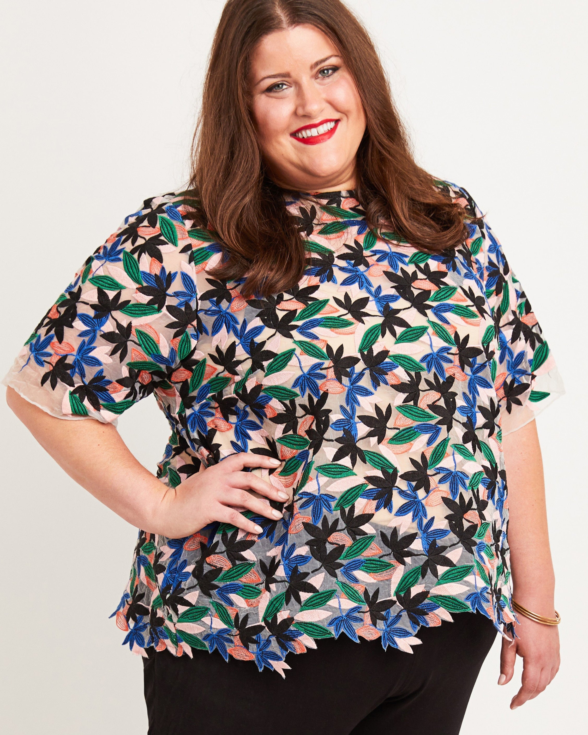 Woman wearing a colorful floral blouse against a plain background. This top is the Montrose Top sewing pattern from Cashmerette.