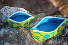 Image of yellow and blue Rivet Patterns Prelude Pouch sitting on rock