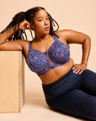 Woman wearing a blue patterned sports bra and navy leggings against a beige background. This is the Cashmerette Somerville Sports Bra sewing pattern for big boobs.