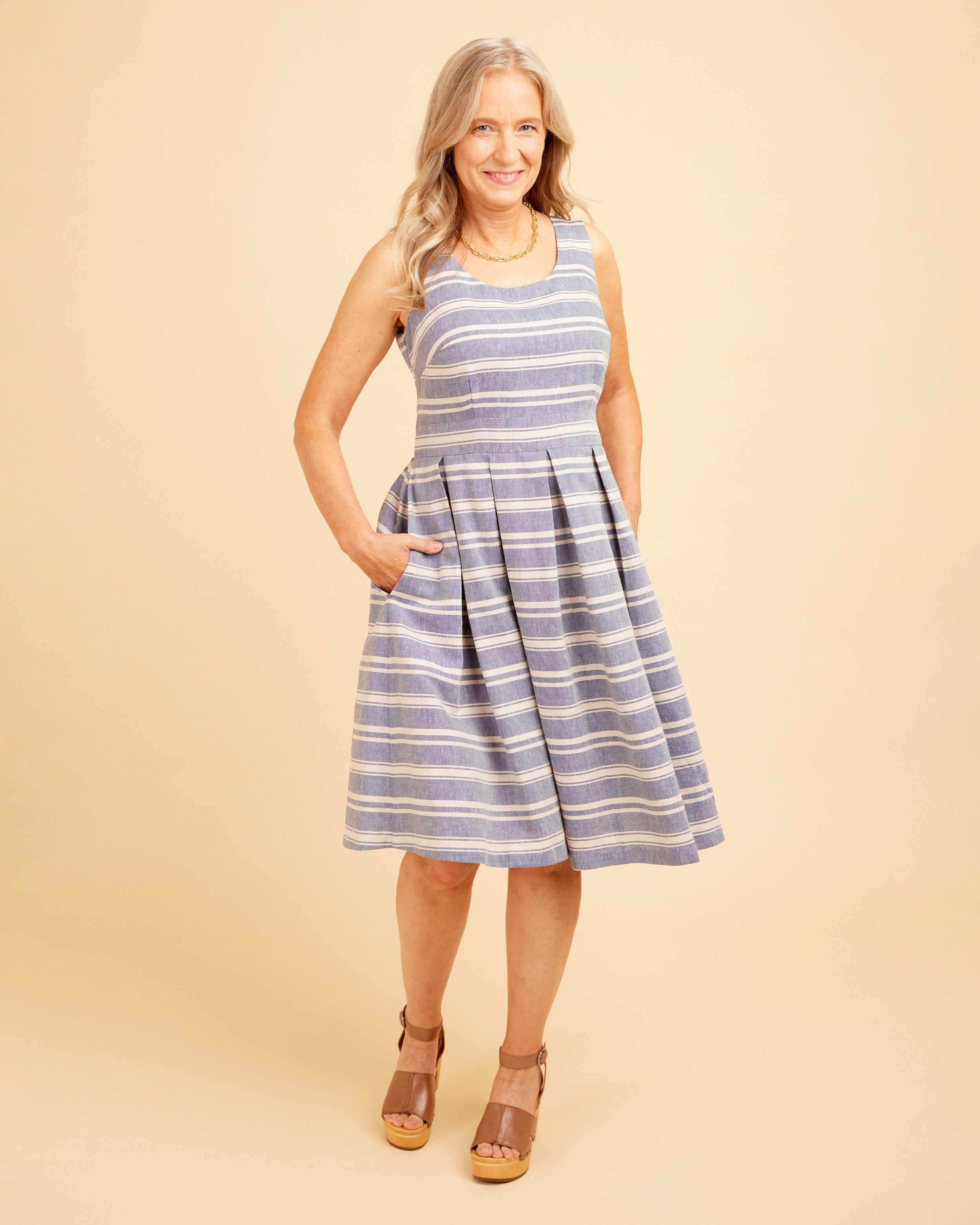 Woman wearing a blue and white striped dress on a beige background. This dress is the Upton Dress & Skirt sewing pattern from Cashmerette.