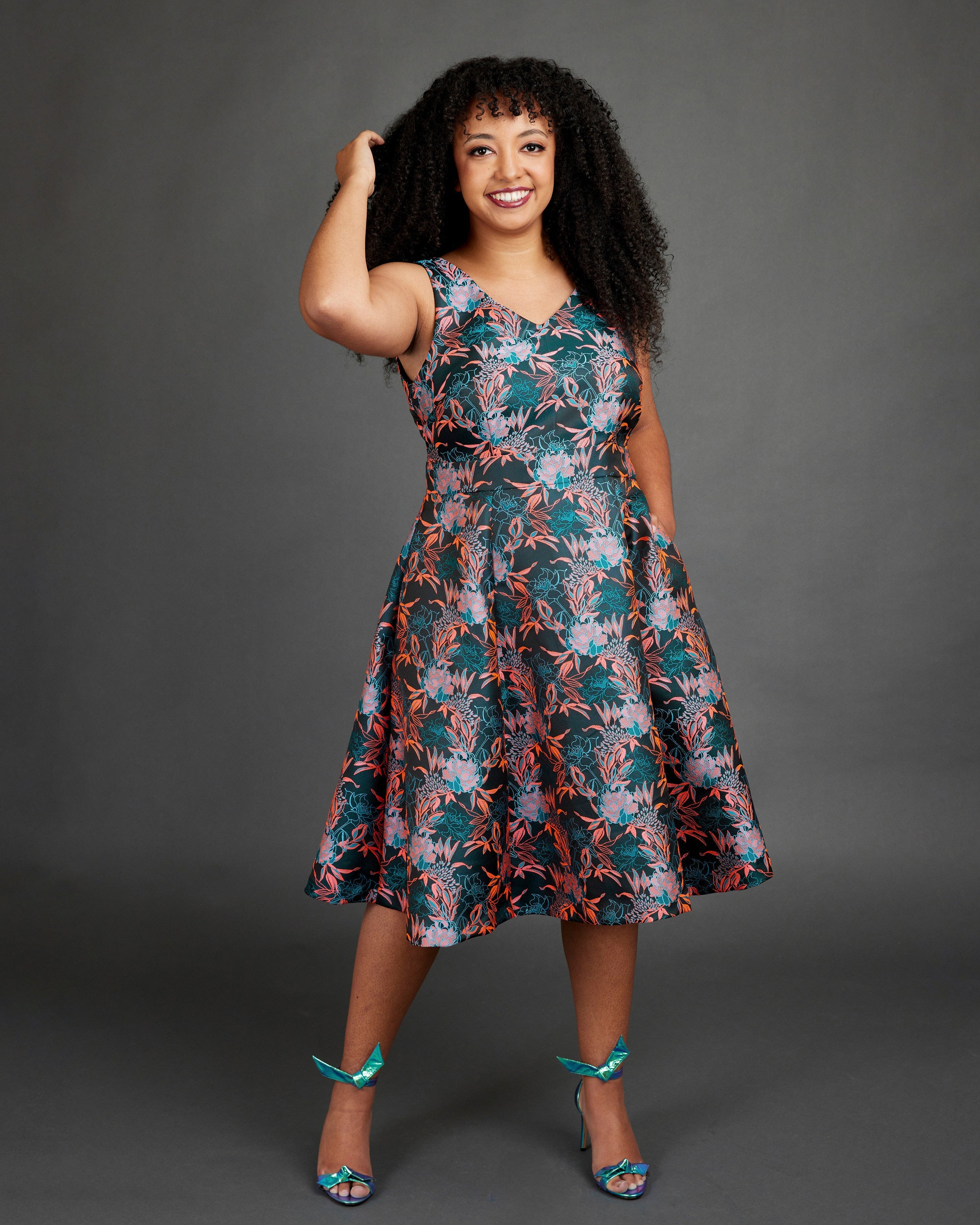 Woman wearing a floral dress against a gray background. This dress is the Upton Dress & Skirt sewing pattern from Cashmerette.