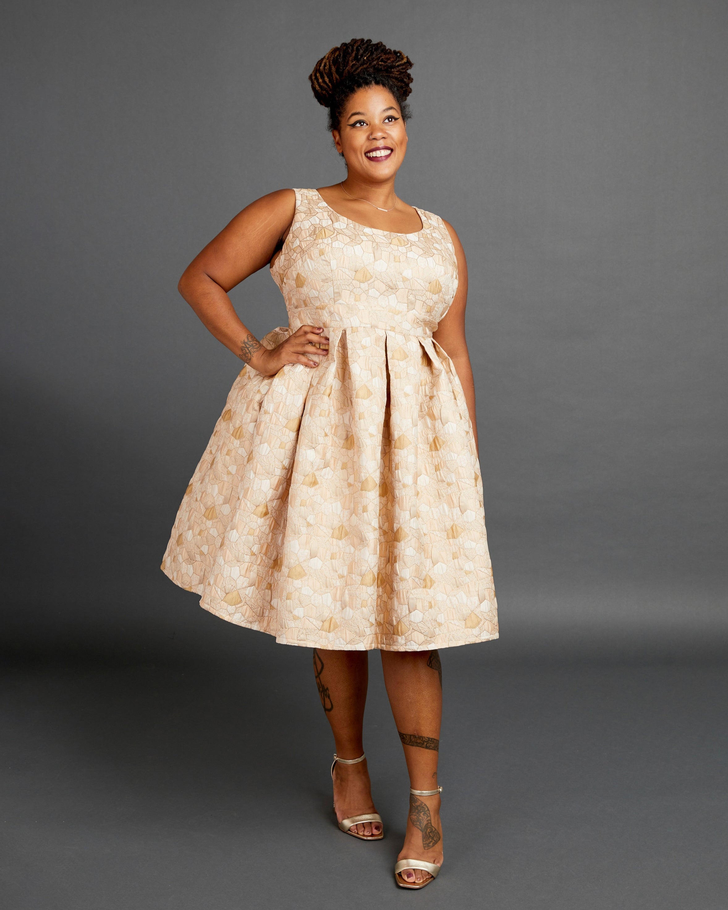 Woman wearing a beige floral dress against a gray background. This dress is the Upton Dress & Skirt sewing pattern from Cashmerette.