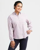 Woman wearing a light purple button-up shirt and dark pants on a white background. This top is the Vernon Shirt sewing pattern from Cashmerette.