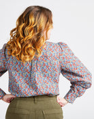 Woman wearing a floral blouse with long sleeves on a plain background. This top is the Vernon Shirt sewing pattern from Cashmerette.