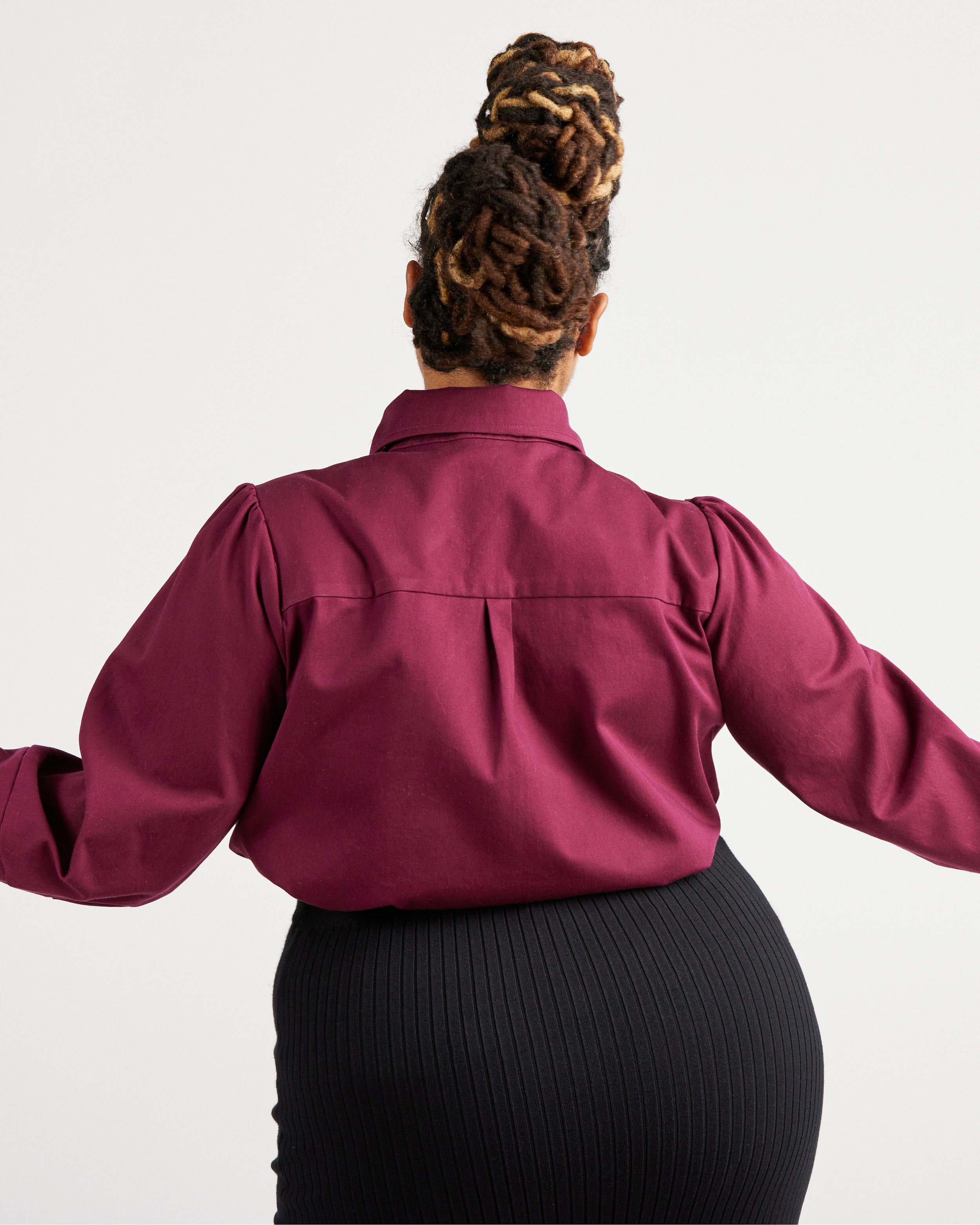 Person wearing a burgundy shirt with long sleeves on a white background. This top is the Vernon Shirt sewing pattern from Cashmerette.