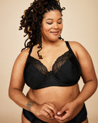 Woman wearing a black lace bra against a beige background. This bra is the Willowdale Bra sewing pattern from Cashmerette.